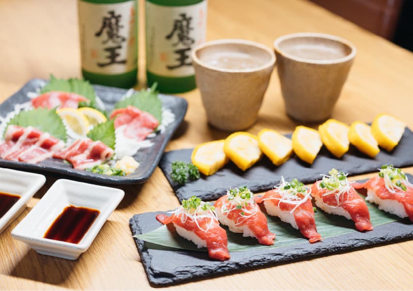 写真：それぞれの皿に盛り付けられたお寿司と辛子蓮根。グラスに注がれた魔王