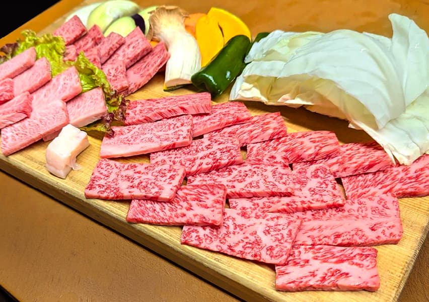 写真：大きな木の皿に盛り付けられた牛肉3種類と数々の野菜