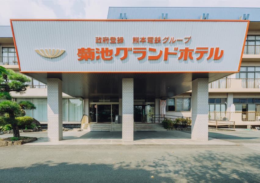 写真：白地の壁にオレンジでホテル名が入っている、菊池グランドホテルの正面玄関